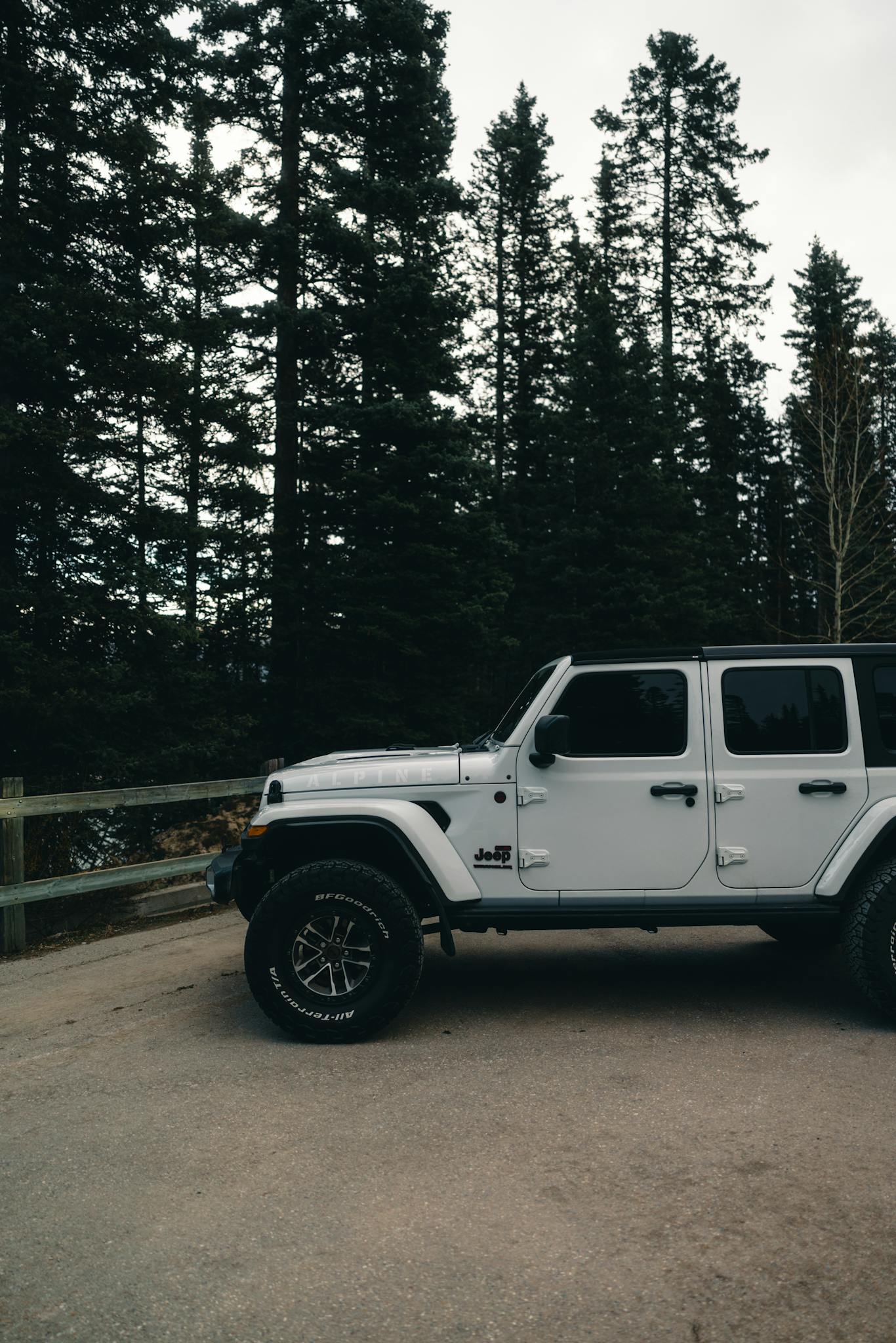 A rugged Jeep parked amidst the towering pine trees of Banff National Park, Alberta.