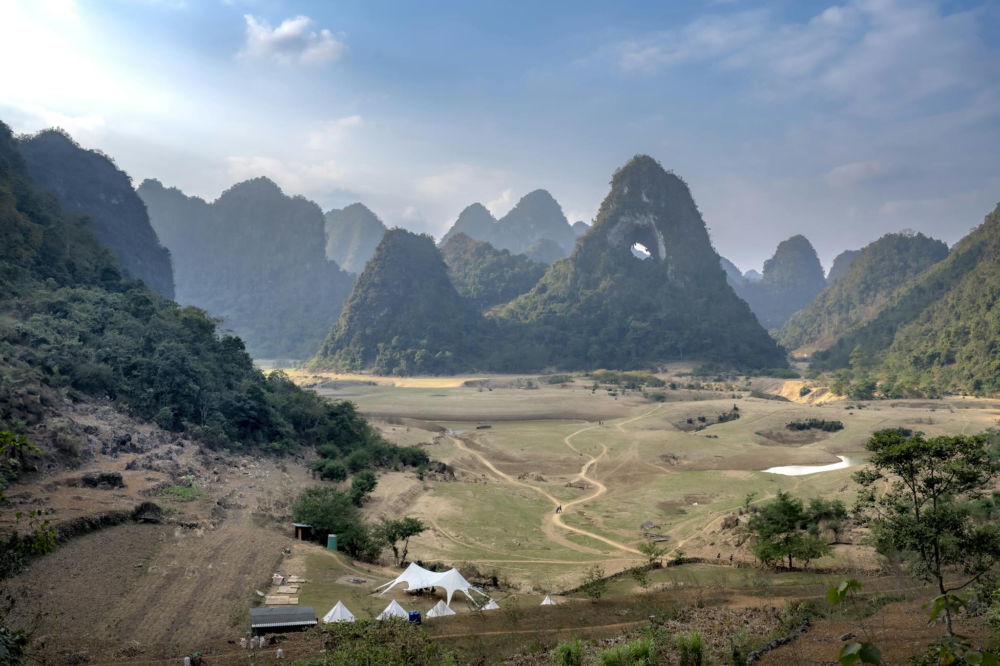 Scenic view of majestic mountains and tents in a serene valley.